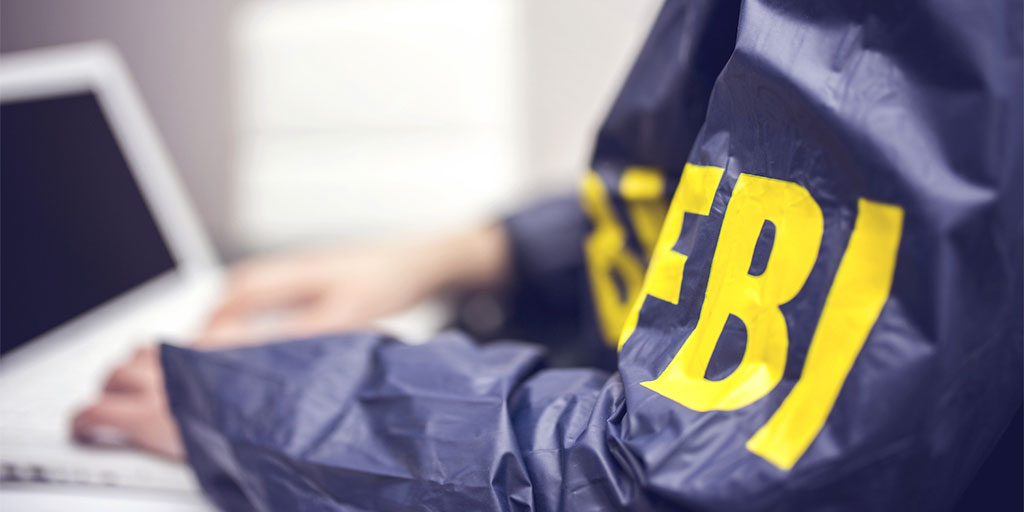 Pessoa teclando vestida de capa azul do FBI