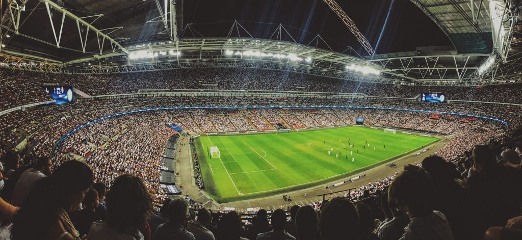 Foto de estádio de futebol com arquibancadas lotadas e times em campo