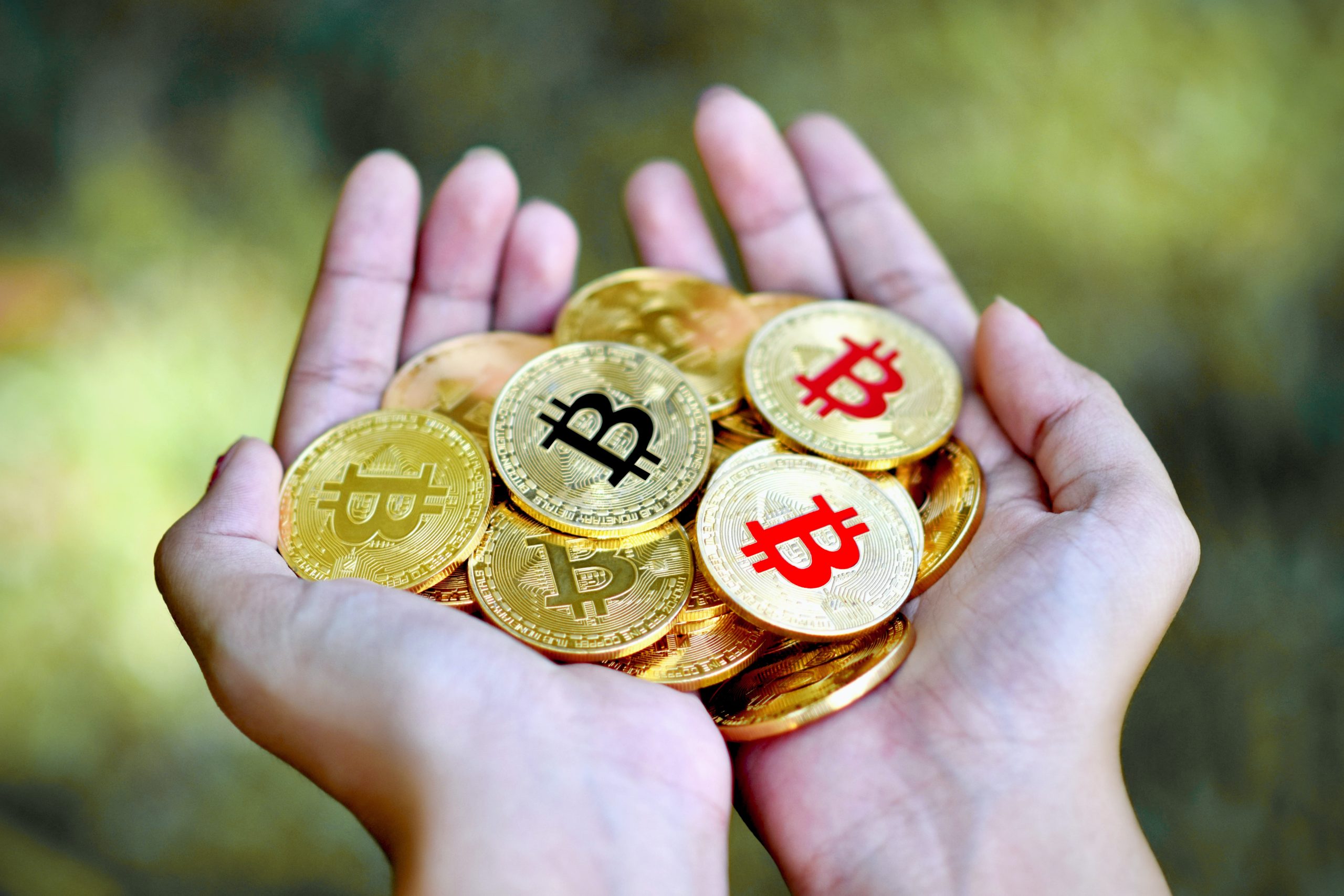 mão segurando diversas moedas de bitcoins